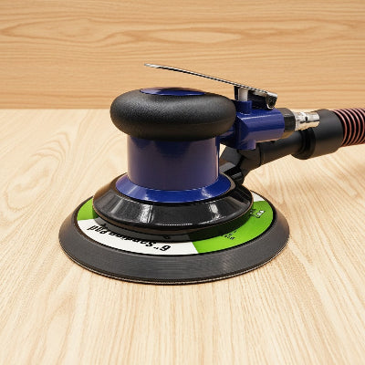 Ponceuse pneumatique professionnelle sur fond bois clair