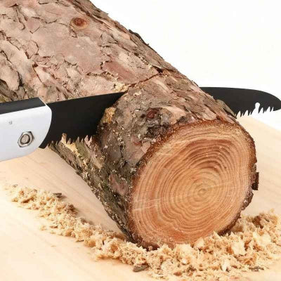 Scie pliante blanche utilisée pour couper une petite bûche