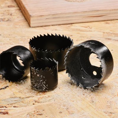 Différents diamètres de scie cloche noires sur un établi