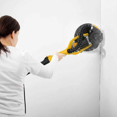 Femme ponçant un mur avec la ponceuse girafe jaune