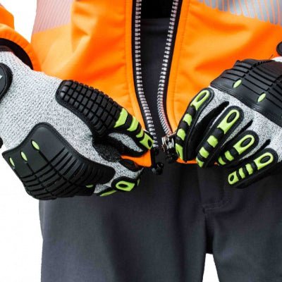 Un homme portant des gants de travail gris monte la fermeture éclair de son manteau
