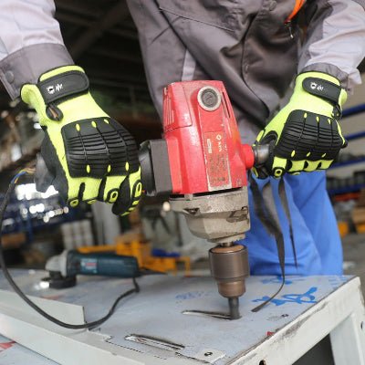 Un travailleur utilise un marteau piqueur en le tenant avec ses gants de travail jaune 