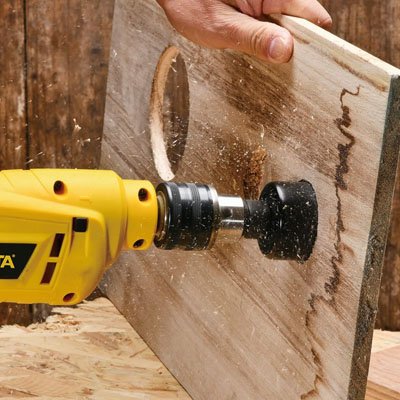 Homme percant une vieille planche de bois avec la scie cloche