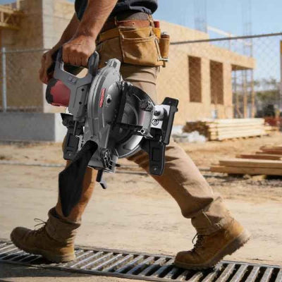 Homme transportant scie a onglet sur chantier construction