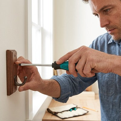 Homme utilisant tournevis pour fixation crochet