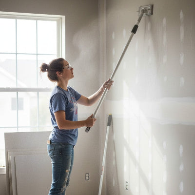 Ponceuse à main jeune femme ponçant un mur placoplâtre