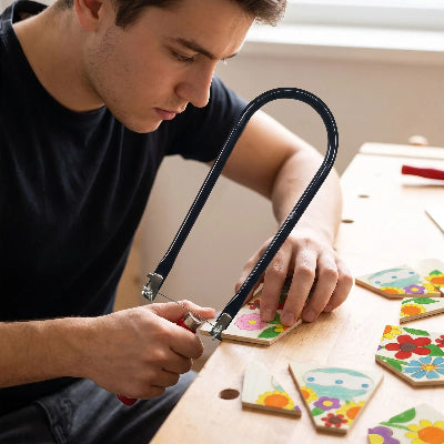 Jeune homme utilisant la scie de précision pour découper un puzzle 
