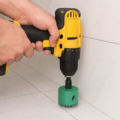 Mains d'homme perçant de la céramique avec la scie cloche