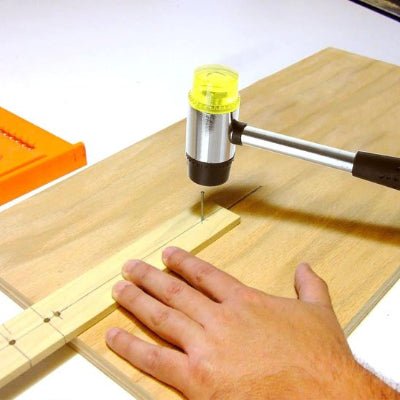 Marteau utilisé pour clouer une règle sur une planche