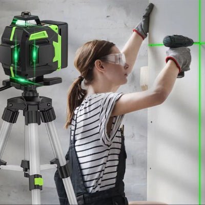 Niveau laser sur trépied et femme perçant un mur avec perceuse visseuse