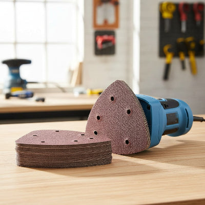 Papier abrasif ponceuse triangulaire sur fond de bois clair