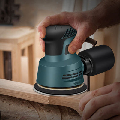 Ponceuse excentrique bleue utilisée sur meuble en bois