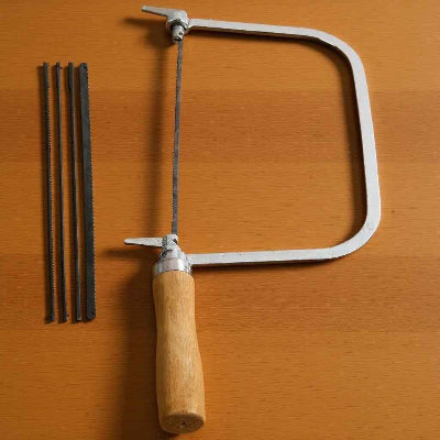 Scie à chantourner professionnelle avec 4 lames sur fond bois
