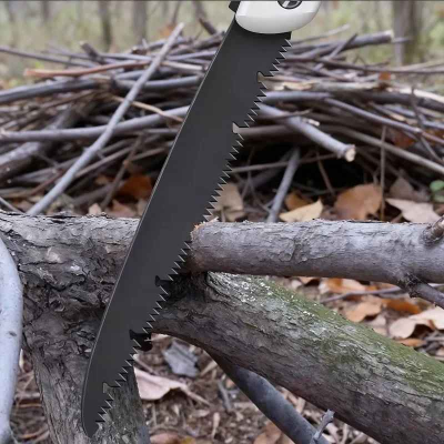 Scie pliante blanche utilisée pour couper des branches dans la forêt